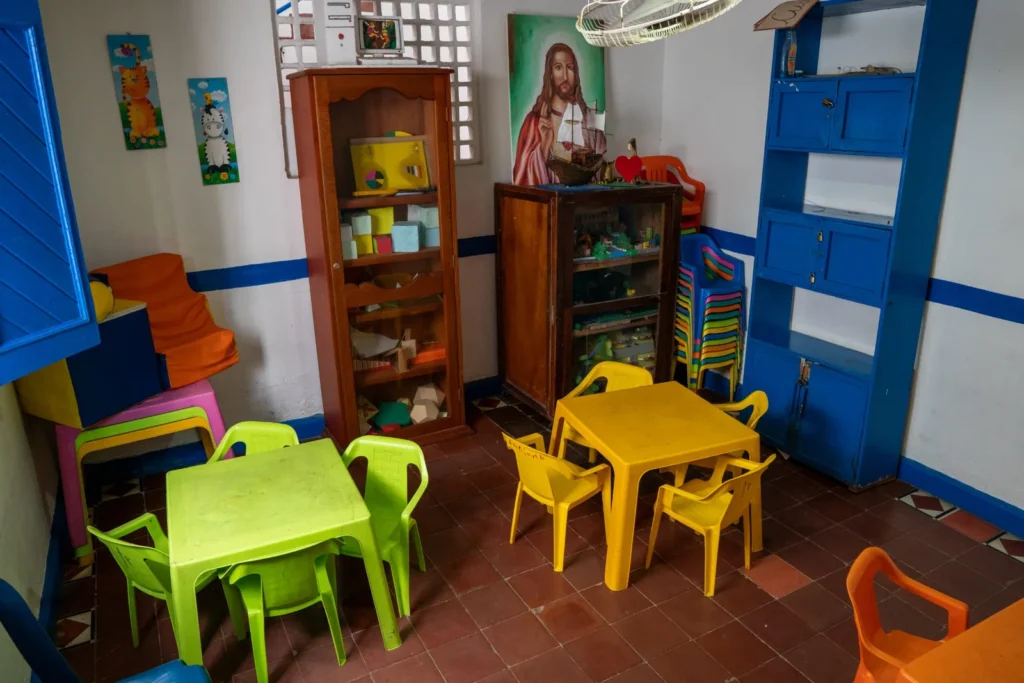 Aula de preescolar con mesas y sillas de colores y estantes con material de juego