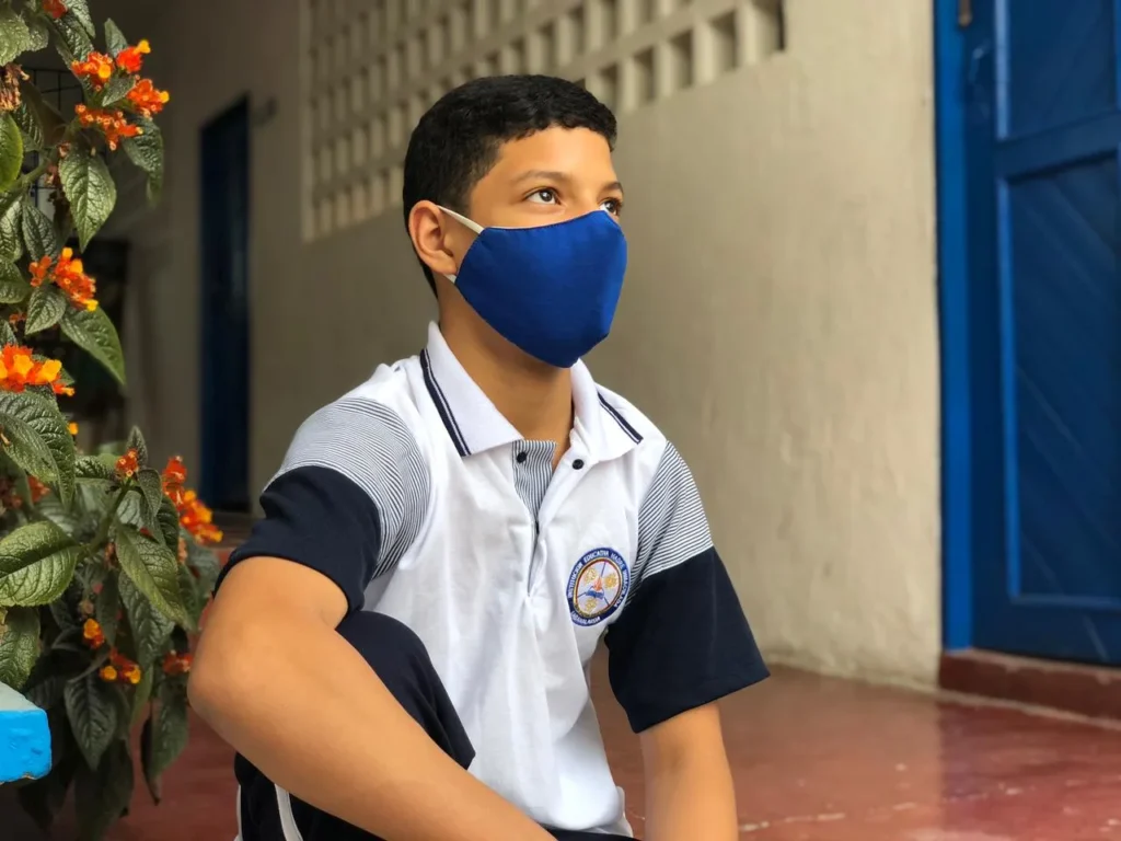 Estudiante con polo institucional sentado en el patio del colegio