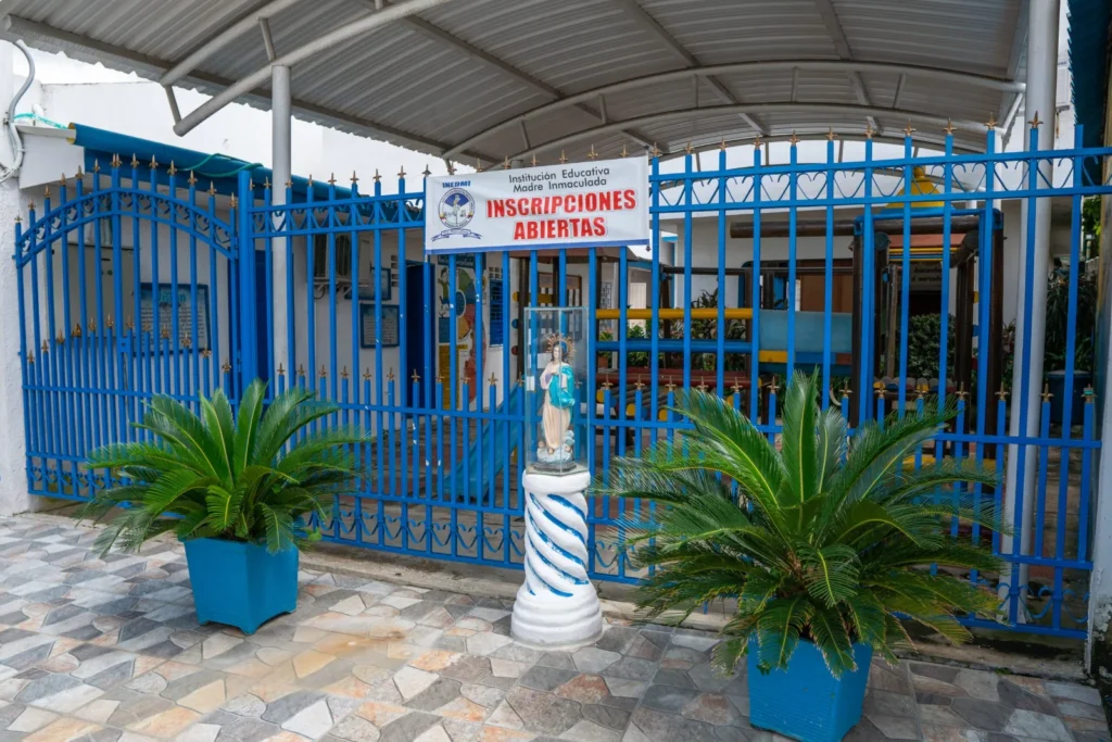 Entrada principal del colegio con portón azul y jardín