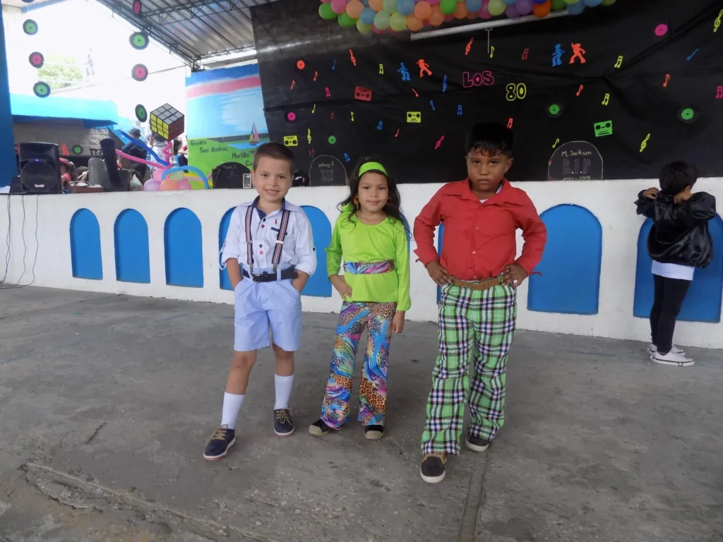 Niños de primaria disfrazados sobre el escenario del patio durante una jornada cultural