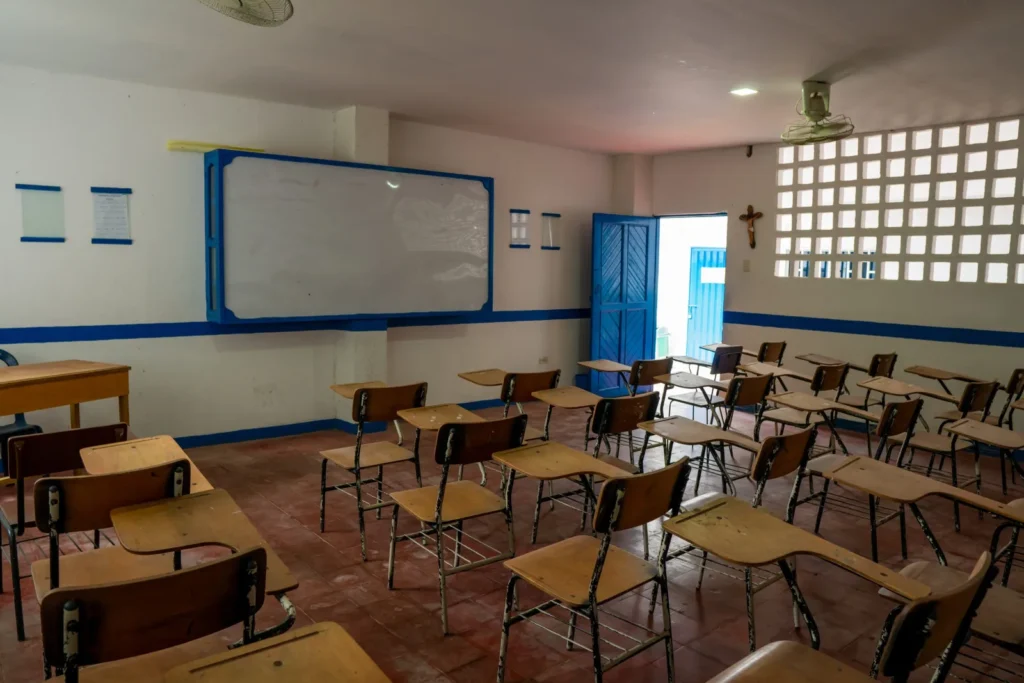 Salón con tablero, pupitres y puerta azul