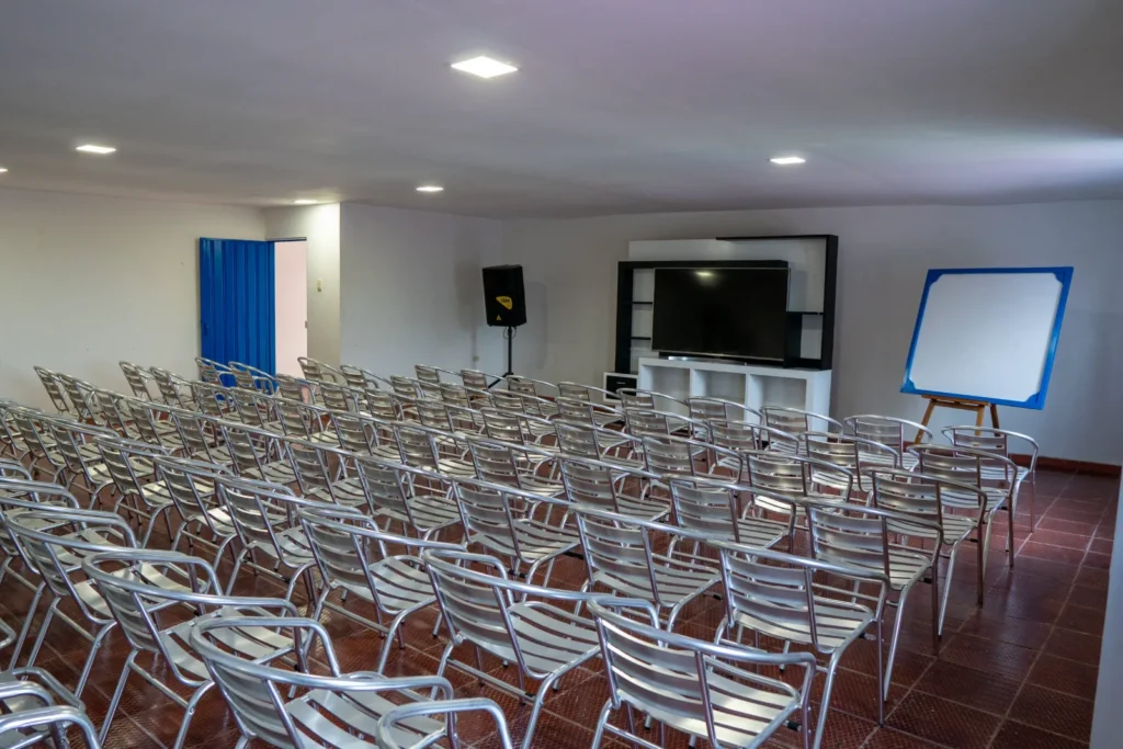 Salón múltiple con sillas, televisor y tablero